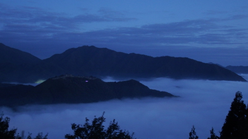 夜明け前の竹田城と周囲の暗い山並み